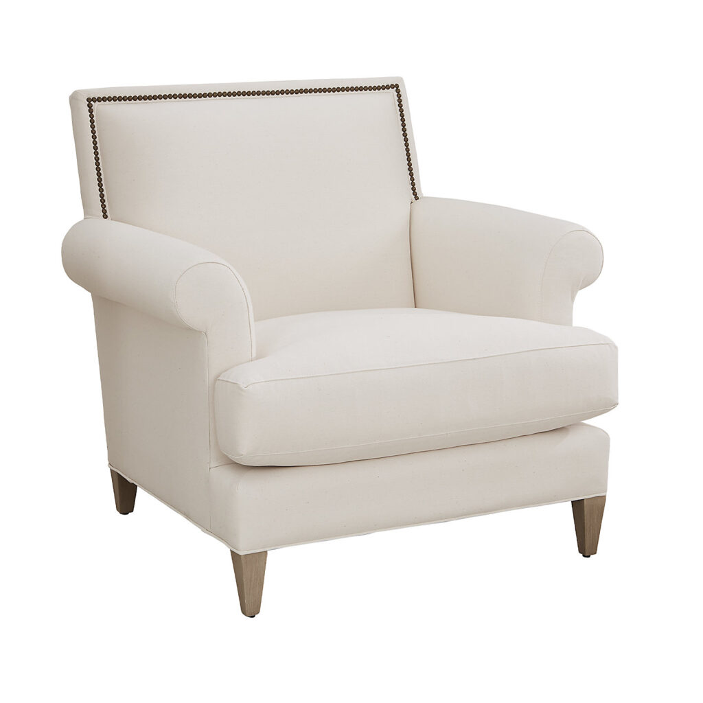 Juliana upholstered armchair in off-white fabric with brass nailhead detail in a refined living room